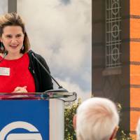 Laura Aikens standing at podium, speaking at event